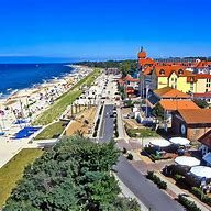 Blick auf einen Strand mit Promenade, Restaurants und blauen Himmel.