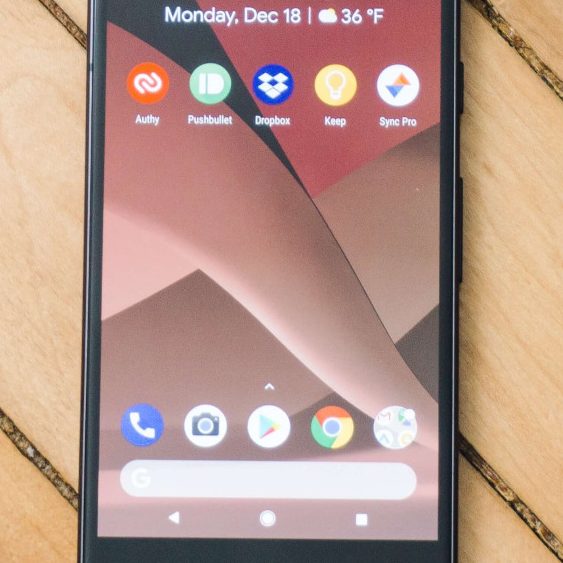 Smartphone mit App-Symbolen auf dem Bildschirm, vor einem Holzuntergrund.