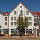 Blick auf ein mehrstöckiges Gebäude mit roten Dächern und Terrassen im Freien.