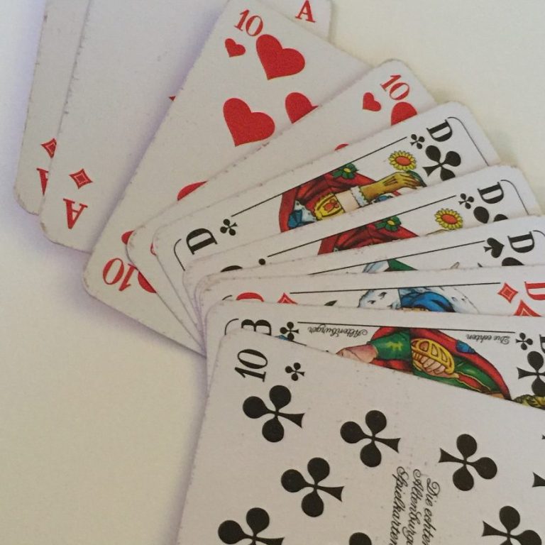 Eine Kartenhand mit verschiedenen Spielkarten, darunter Herzen und Kreuz.